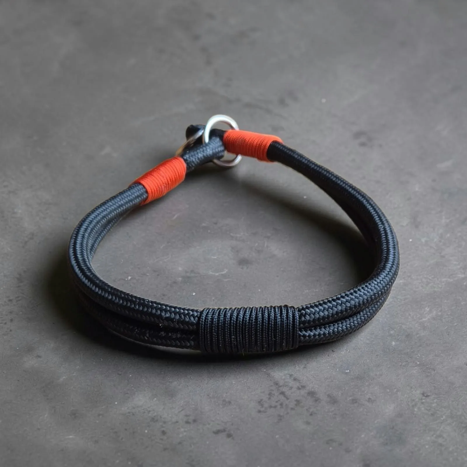 Black rope slip collar with orange whipping and a stainless steel ring