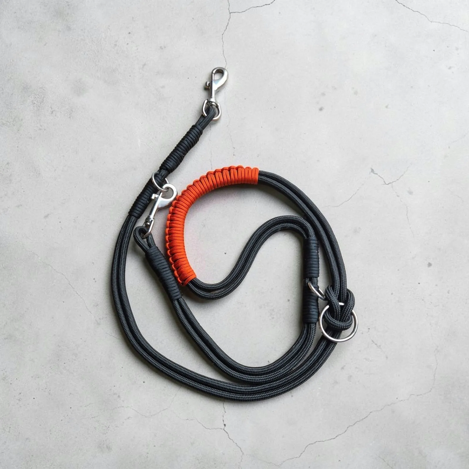 Black rope 3-in-1 lead laid flat with an orange braided handle